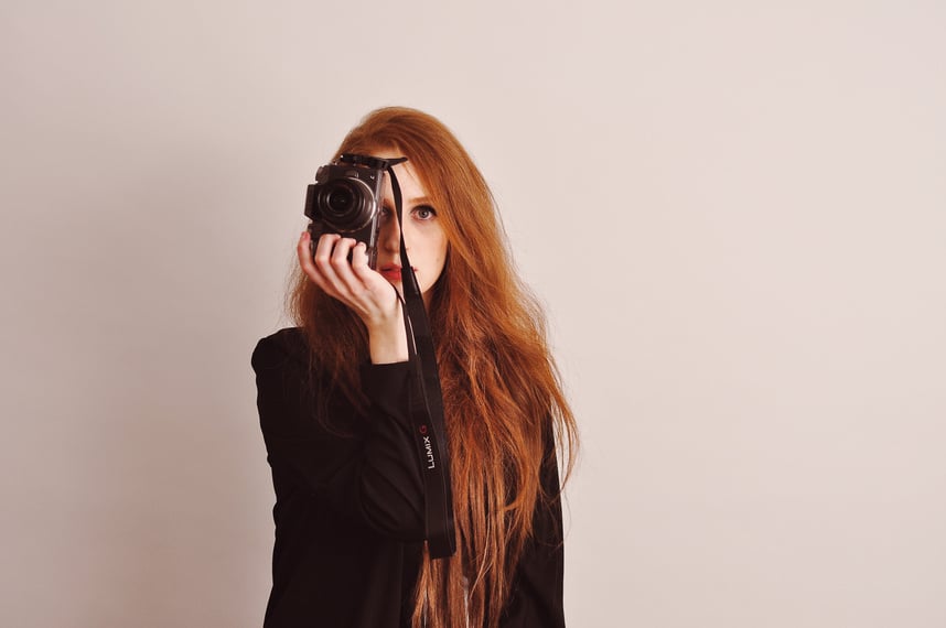 an actress writer creator with long red hair holding a camera