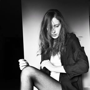 a black and white studio shot of an actor sitting on the floor